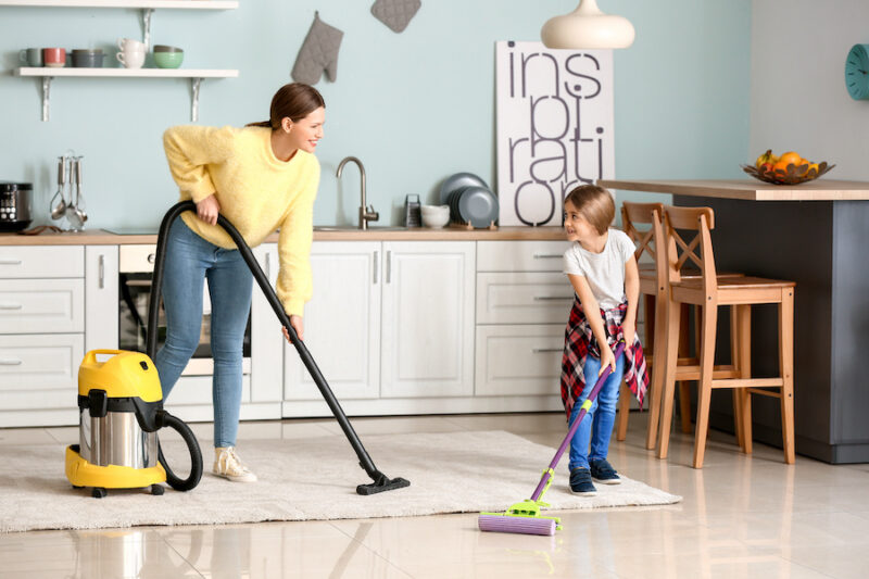 Femme de ménage avec en enfant nettoyant une cuisine